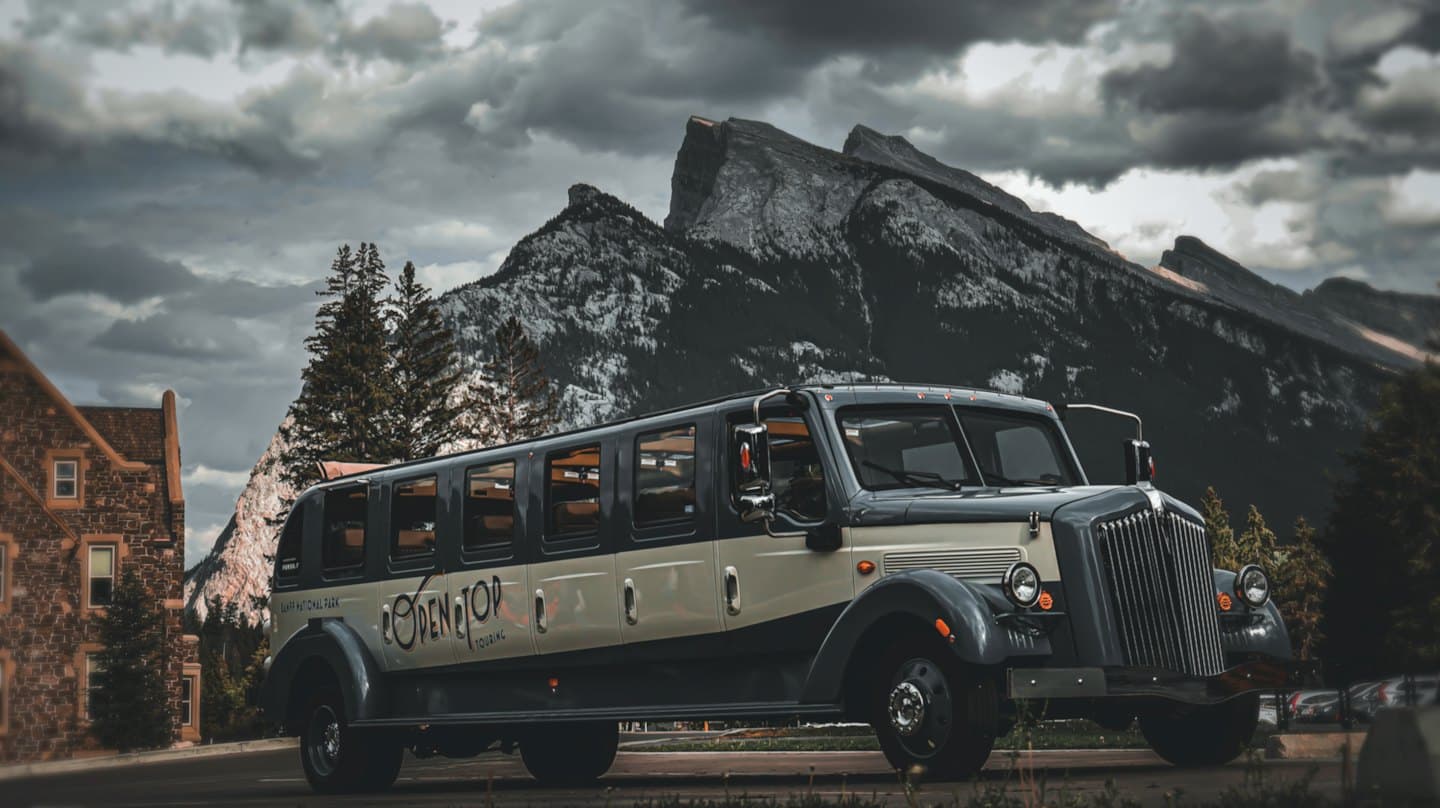 Autobus turistico d'epoca parcheggiato su una strada con montagne innevate.