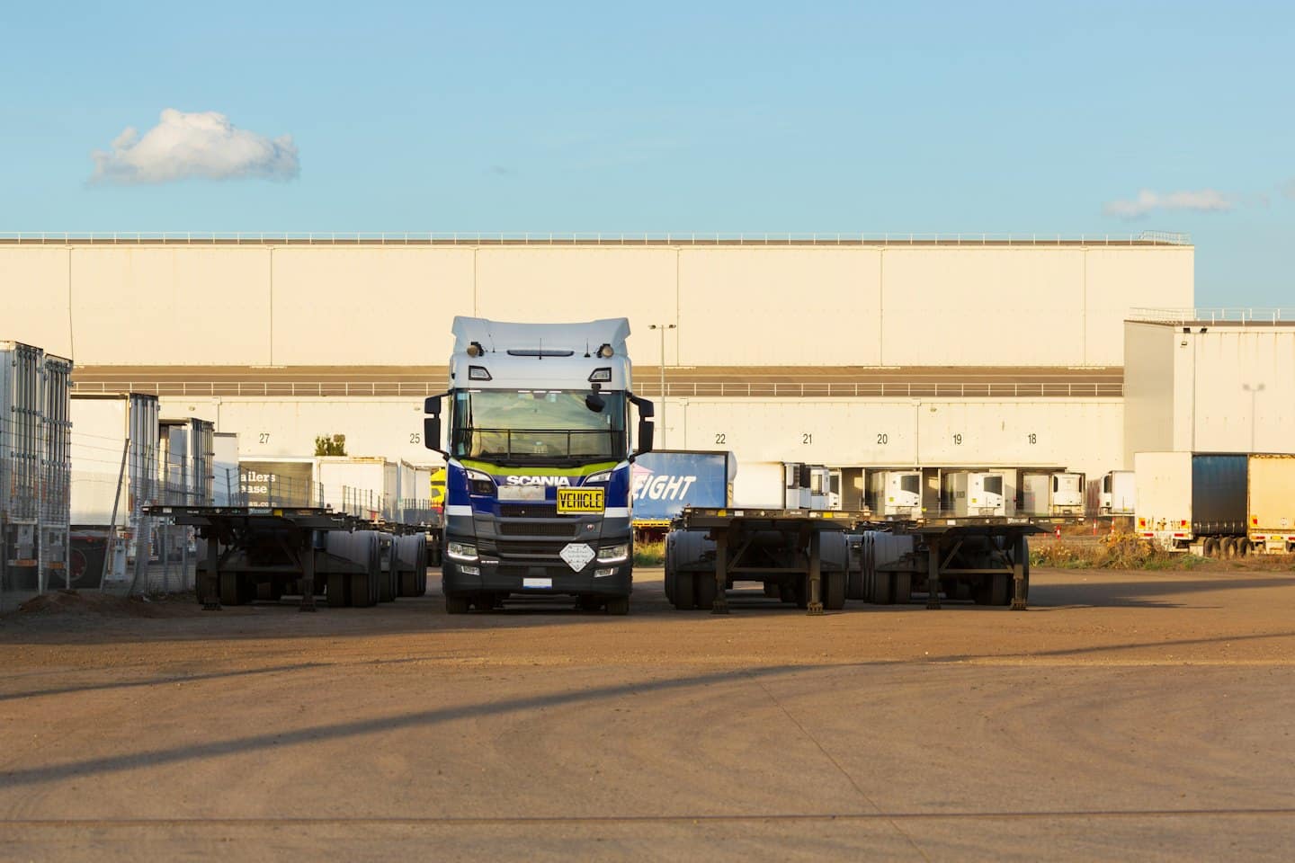 Camion Scania blu e bianco parcheggiato in un cortile logistico.