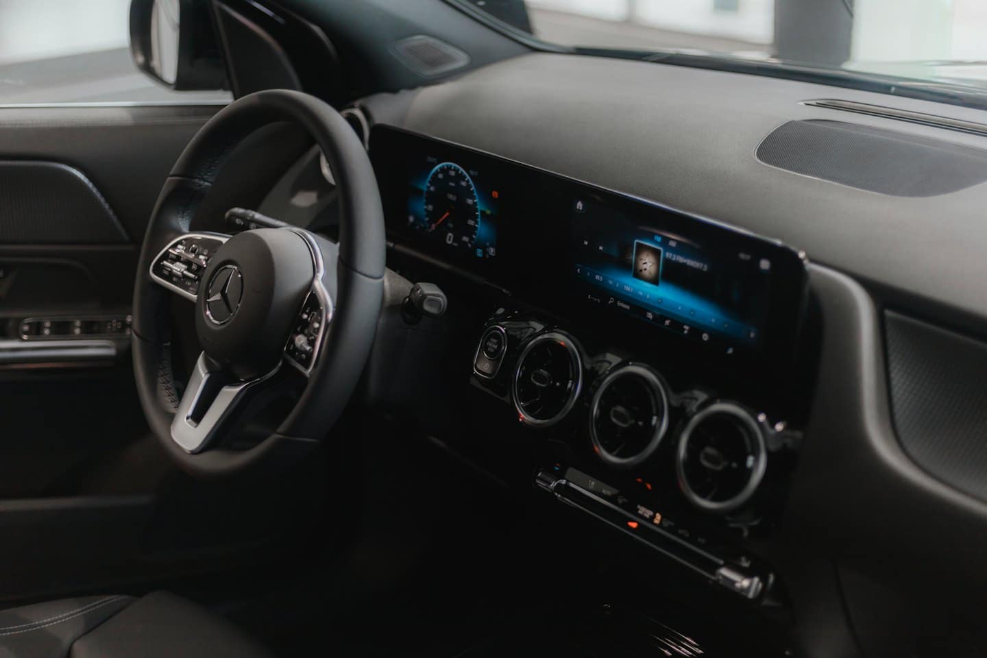 Cruscotto di un'auto di lusso moderna con display digitali illuminati e controlli.